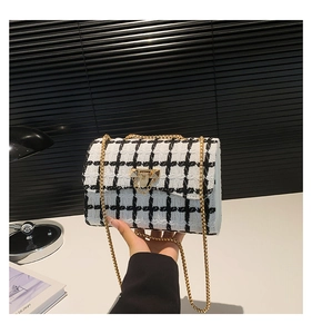 Detail of classic black and white tweed crossbody bag with gold chain and metal clasp