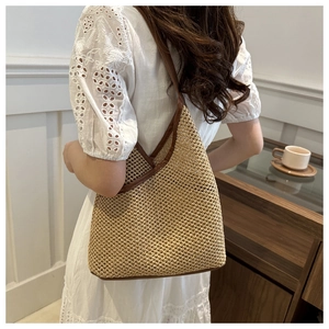 Detail of hand-woven bucket bag with brown leather trim worn by model in white dress
