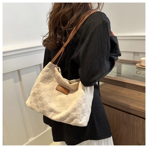 Detail of cream woven tote bag with brown leather straps and fashion label tag