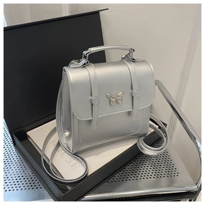 Macro shot of silver PU leather crossbody bag with butterfly metal lock in gift box