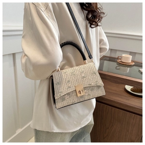 Straw handbag with floral embroidery and gold buckle shown in a lifestyle home setting