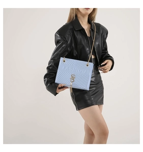 Detail of light blue quilted chain bag with gold logo, fringe tassel and fashion embossing