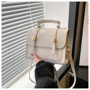 Détail macro du motif marbré et de la boucle dorée sur un sac à main blanc élégant