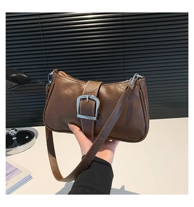 Dettaglio di una borsa a mezzaluna vintage in pelle marrone con fibbia argentata e tracolla