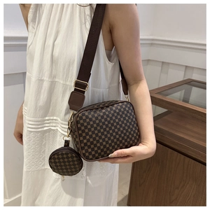 Detail of a brown plaid crossbody bag set with a small round coin purse on a woven strap