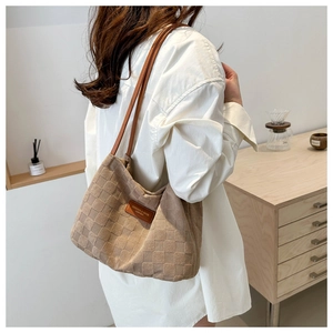 Detail of checkered shoulder tote bag with leather logo tag on a casual white shirt