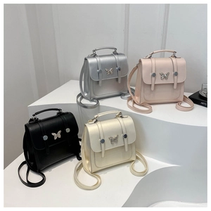 Detailed display of four mini leather backpacks with metallic butterfly buckles in various colors