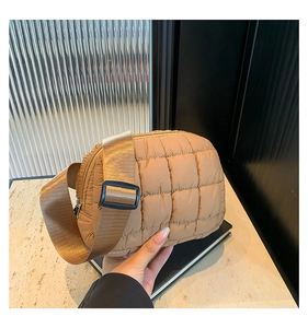 Detalle de bolso acolchado marrón caramelo con correa ancha y diseño de cuadros