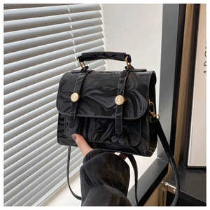 Détail d'un sac à main motif marbre noir avec finition brillante et fermoir doré rond