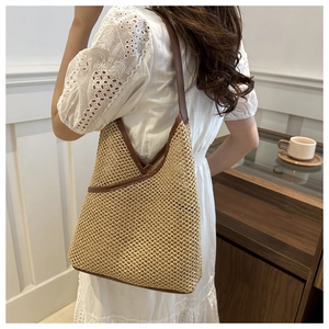 Detail of handwoven straw tote bag with brown leather accents and a minimalist design