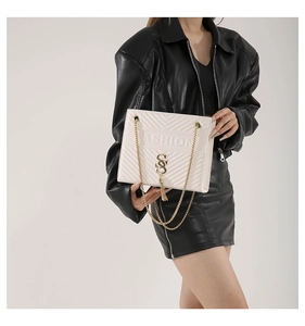 Close-up of cream crossbody bag featuring V-shaped quilting and a gold chain strap