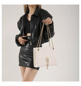 Close-up of cream quilted crossbody bag with golden chain and tassel detail