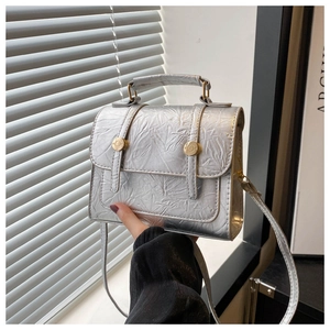 Détail d'un sac à main argenté plissé avec des boucles en métal doré de style rétro