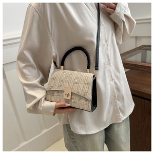 Detail of beige woven handbag with floral embroidery and gold metal twist lock