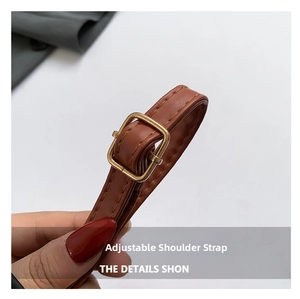 Macro shot of an adjustable brown leather shoulder strap with a golden square buckle