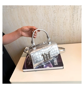 Close-up of silver crocodile embossed texture and metallic M logo on the chic square bag