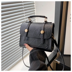 Détail du sac à main noir mat style ballet avec texture cuir plissé et boucles en métal