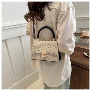 Detail of beige straw crossbody bag with floral embroidery and golden metal clasp