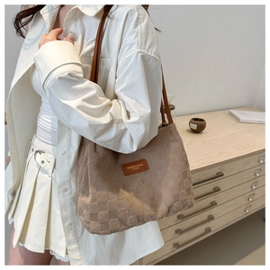 Close-up of light brown checkered tote bag with fashion leather tag on white shirt outfit