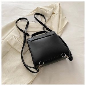 Close-up of black matte leather backpack with silver buckles on a beige blazer background