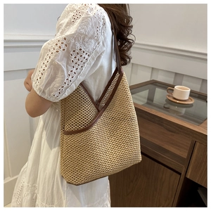Detail of hand-woven straw tote with premium brown leather trim and shoulder strap