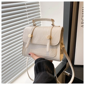 Détail d'un sac à main blanc en cuir texturé avec deux boucles métalliques dorées