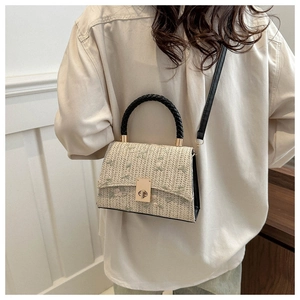 Detail of floral embroidery on straw crossbody bag with golden metal twist lock closure