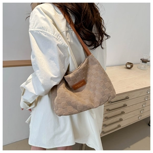 Detail of beige tote bag with textured checkerboard pattern and brown leather straps