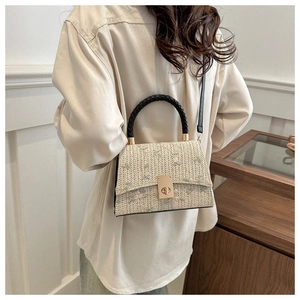 Close-up of woven handbag with floral embroidery and gold metal twist lock detail
