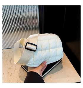 Detalle de bolso bandolera acolchado beige con textura suave y correa ajustable