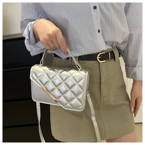 Detail of silver quilted handbag with metallic finish and minimalist metal trim bar