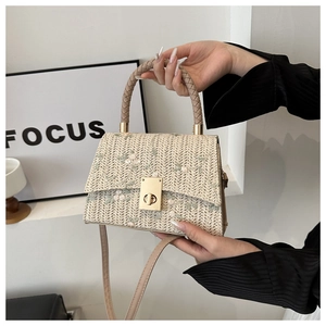 Detail of straw woven bag featuring floral embroidery and a square gold metal clasp