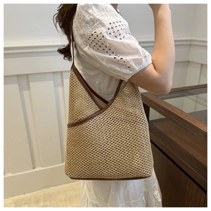 Detail of handmade straw shoulder bag with brown leather trim and half-moon structure