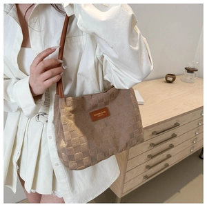 Close-up of a brown woven texture tote bag featuring a leather logo patch on the front