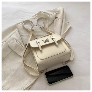 Close-up of cream white backpack with silver butterfly detail on textured leather