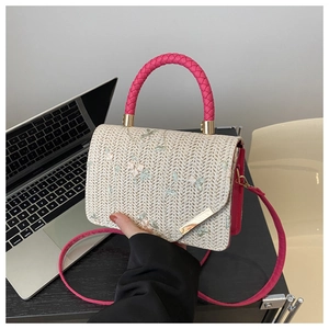 Detail of straw woven bag with floral embroidery and pink circular woven handle