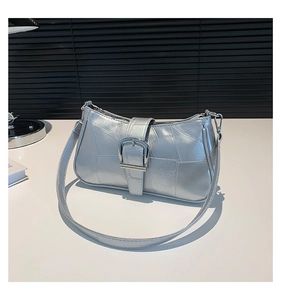 Primo piano della borsa baguette argento metallizzato con trama patchwork e fibbia in metallo
