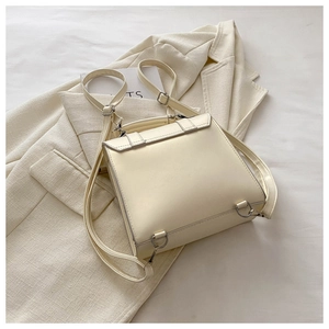 Detail of a structured cream faux leather backpack with silver hardware and top handle