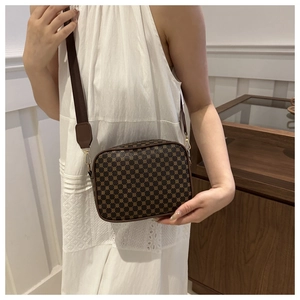 Detailed close-up of brown vintage crossbody bag with patterned texture and wide strap