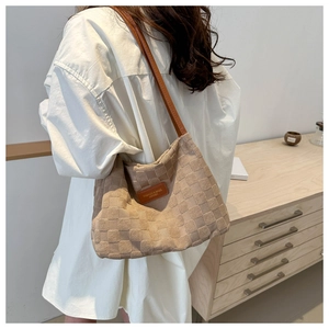 Detail of light beige tote bag featuring 3D quilted texture and brown leather strap