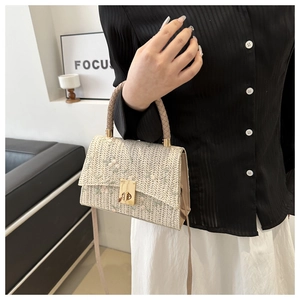 Detail of floral embroidery on beige straw handbag with gold metallic twist lock closure