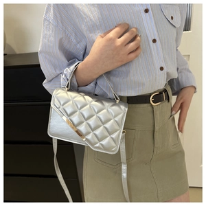 Close-up of a silver quilted small square bag with metallic finish and gold hardware accents