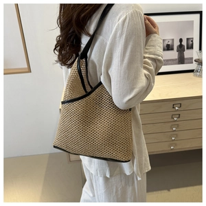 Close-up of beige handmade straw bucket bag with black leather trim and hollow-out weave