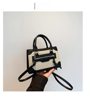 Détail de la texture tissée beige et des coutures en cuir noir sur un mini sac à main