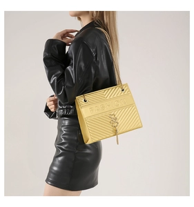 Detail of yellow V-quilted chain bag with FASHION text worn with a leather jacket