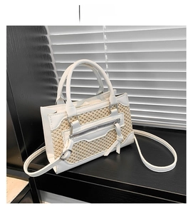 Détail du sac à main en paille tissée avec bordure en cuir blanc et zip métallique