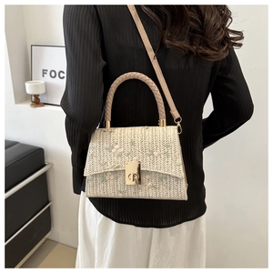 Detail of cream straw crossbody bag featuring green floral lace embroidery and gold clasp