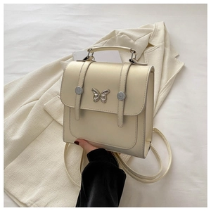 Close-up of cream faux leather bag with metallic butterfly clasp and elegant texture