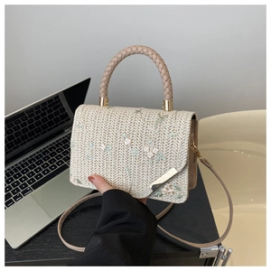 Detail of straw woven handbag with floral embroidery and textured top handle