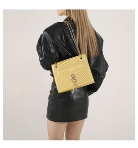 Detail of gold chain shoulder bag featuring V-shaped quilting and a stylish tassel charm